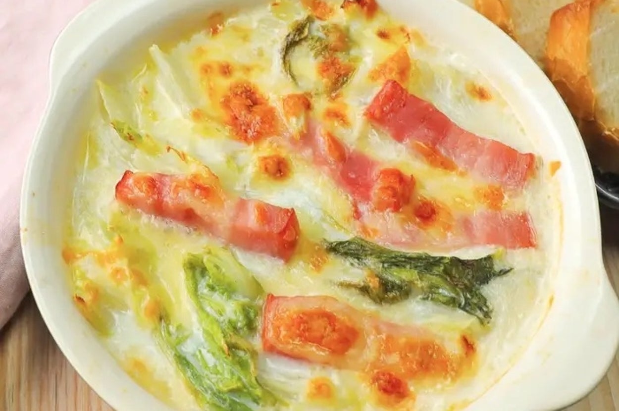 グラタンの皿にベーコン、キャベツ、トマトがのっている。脇にパンが添えられている。