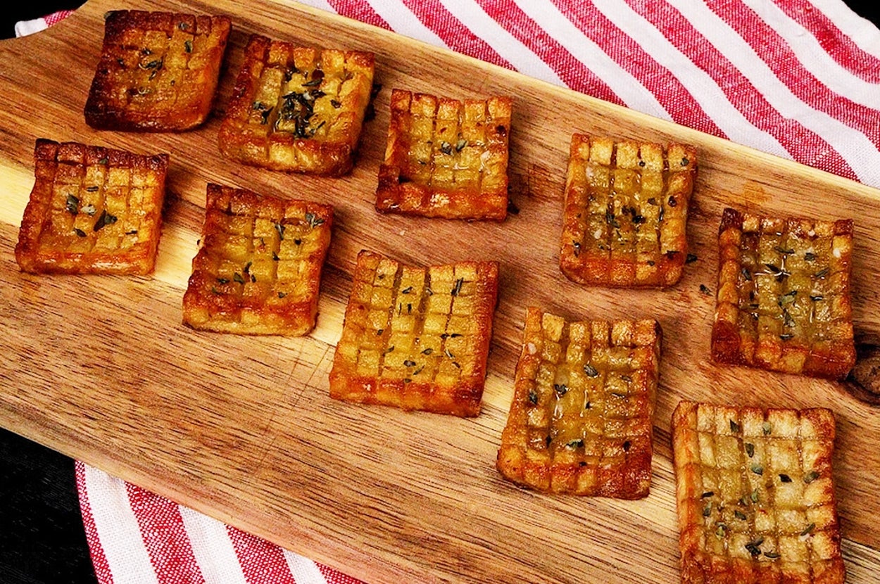 木製のまな板にのった焼いたクラッカーが10枚、ストライプの布の上に置かれています。