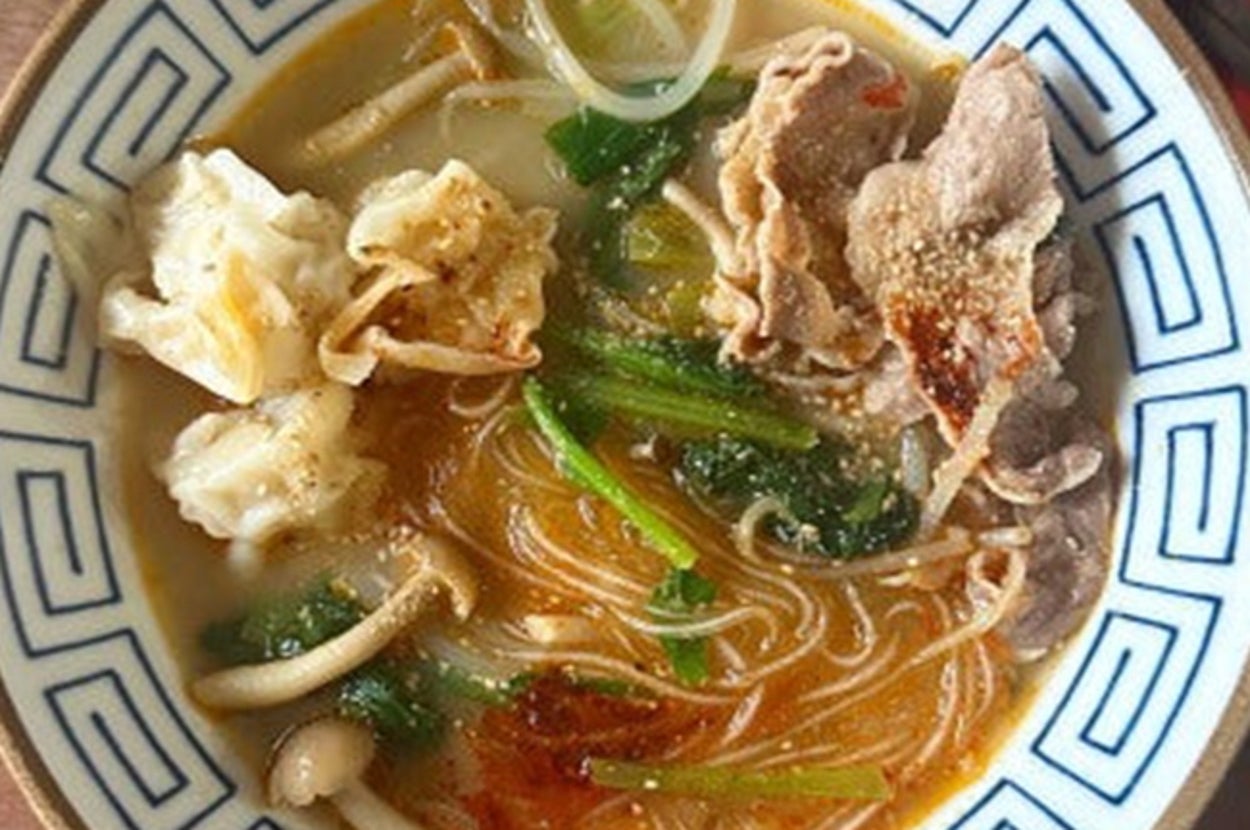 ラーメンの器に麺、しゃぶしゃぶ肉、餃子、野菜が盛られている上から見た写真。