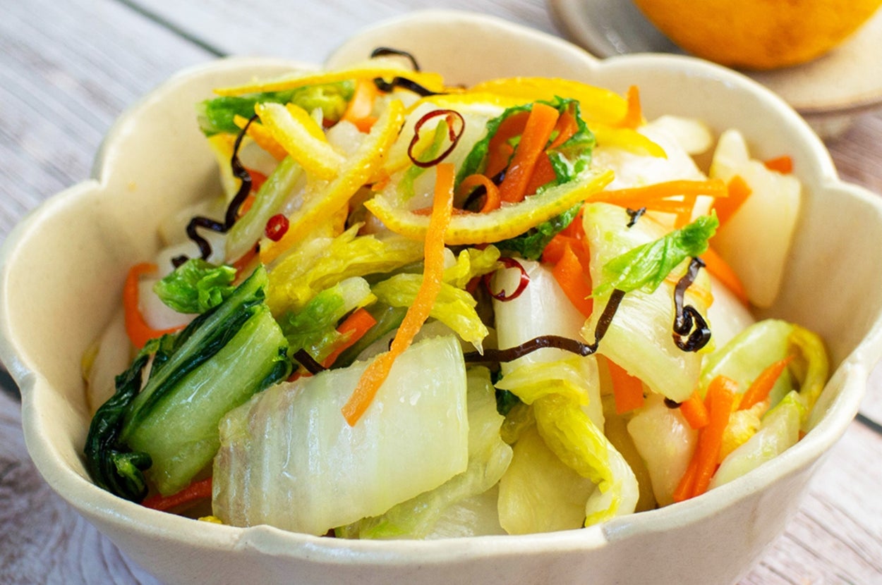 サラダボウルに盛られた新鮮野菜と隣に置かれたレモン。