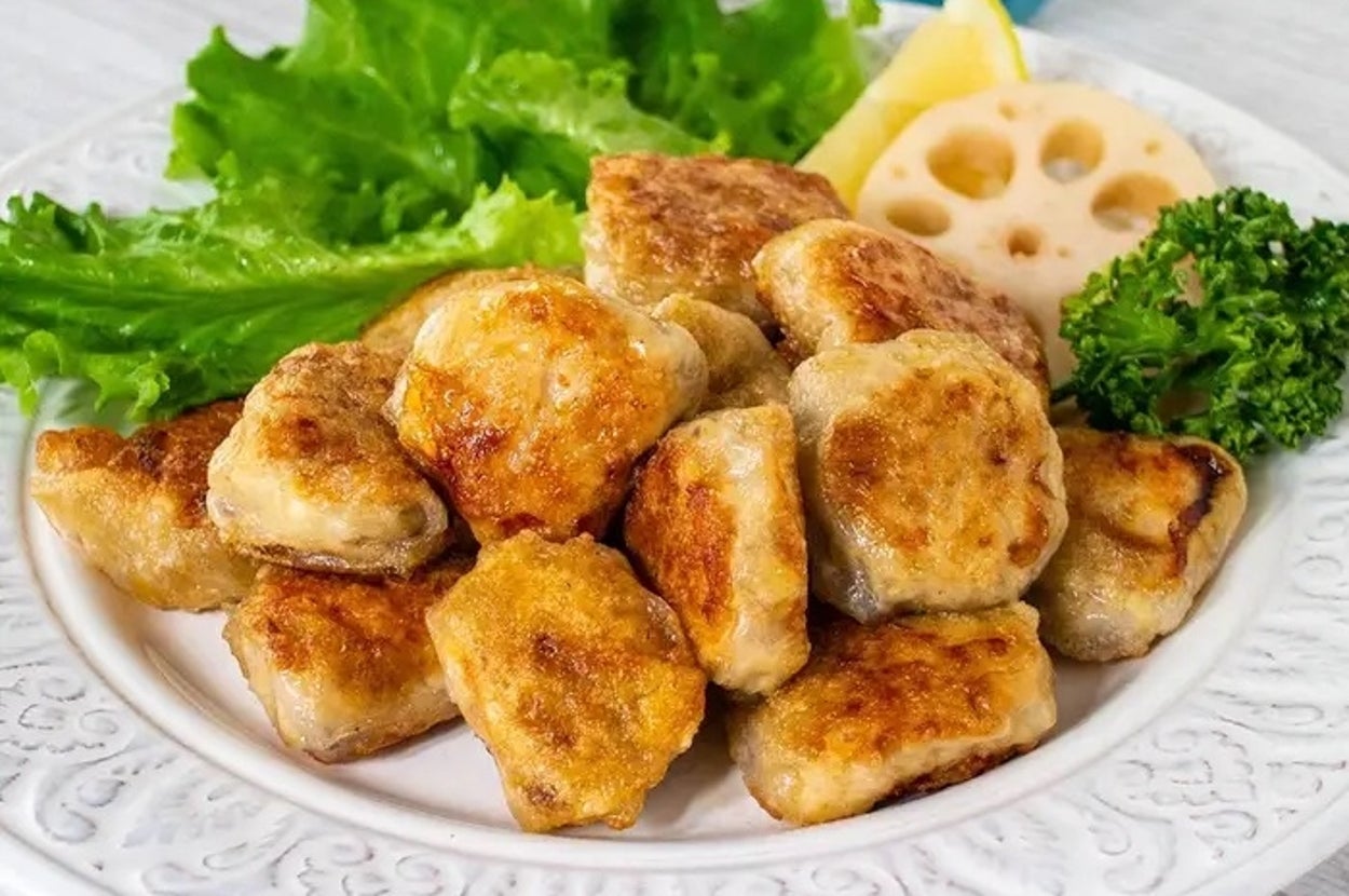 お皿に盛られた焼き餃子がレタス、レンコン、パセリ、ディップと共に提供されている。