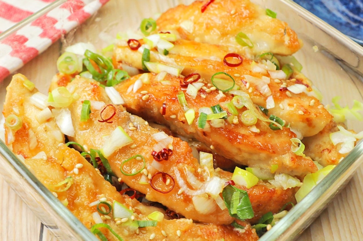 ガラス容器に並んだ焼き餃子。ネギと唐辛子が上に散らされている。