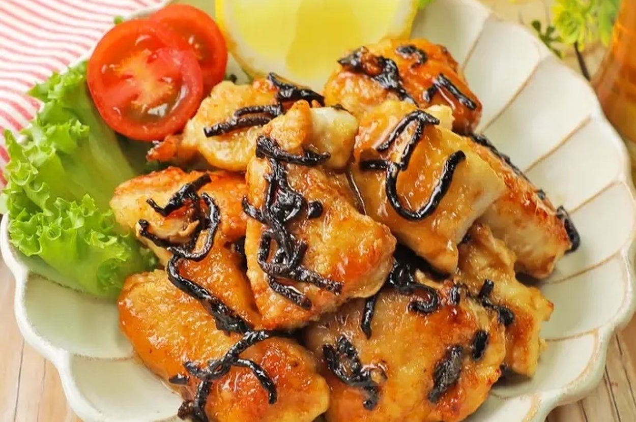 皿に盛られた鶏の照り焼き。レタス、トマト、レモンが添えられている。