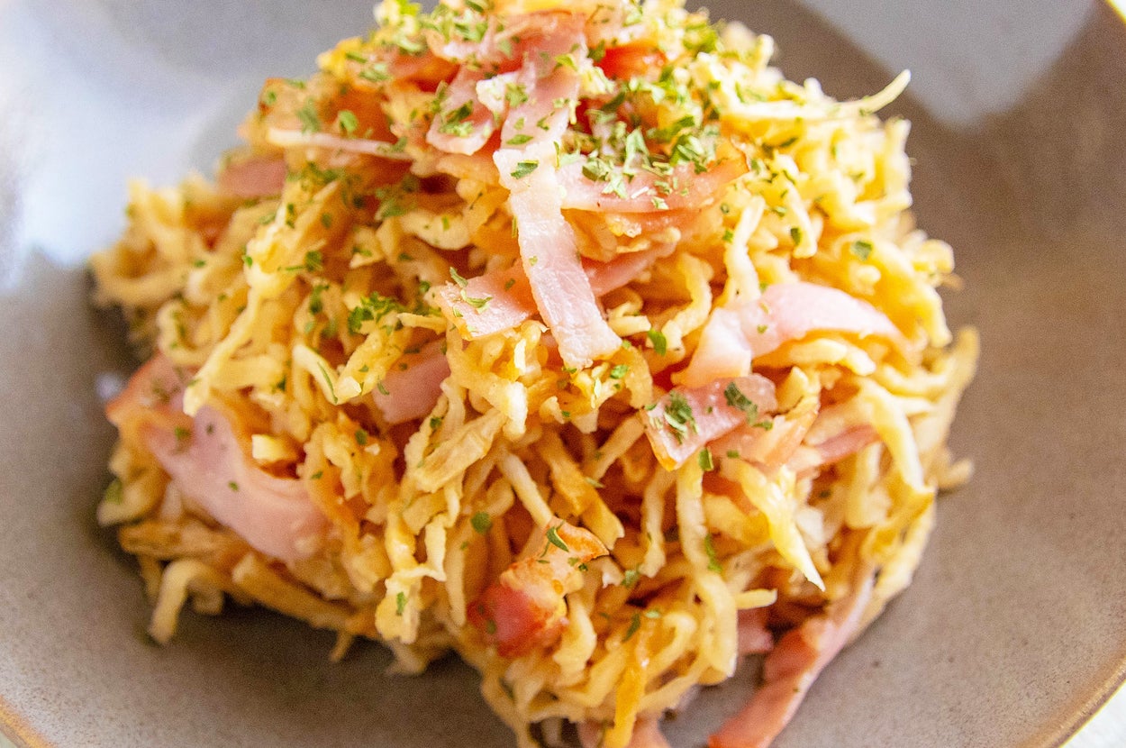 焼きそばの上にベーコンとハーブが載せられた料理。シンプルで美味しそうな盛り付け。