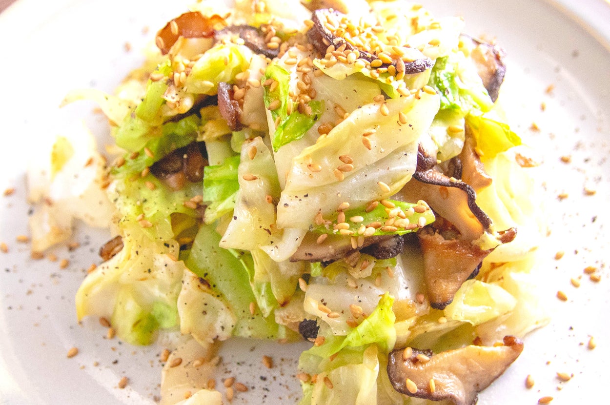 キャベツとしいたけの炒め物が皿に盛られている。ゴマが散らされ、シンプルで美しい盛り付け。