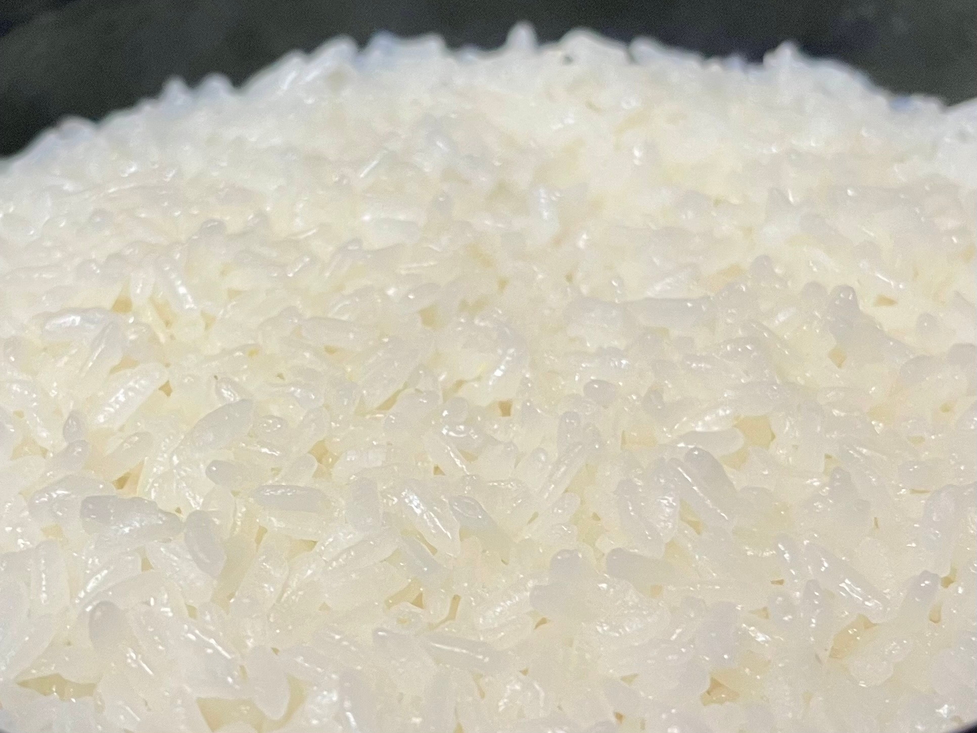 炊き立ての白米のクローズアップ画像。炊飯器またはボウルに盛られ、光沢がありふっくらして見える。