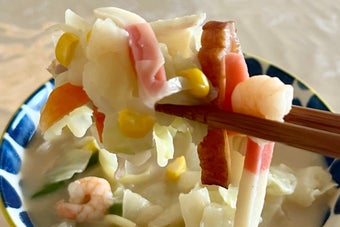 箸で持ち上げられたちゃんぽんの一部が、野菜やシーフードと共に映っている。