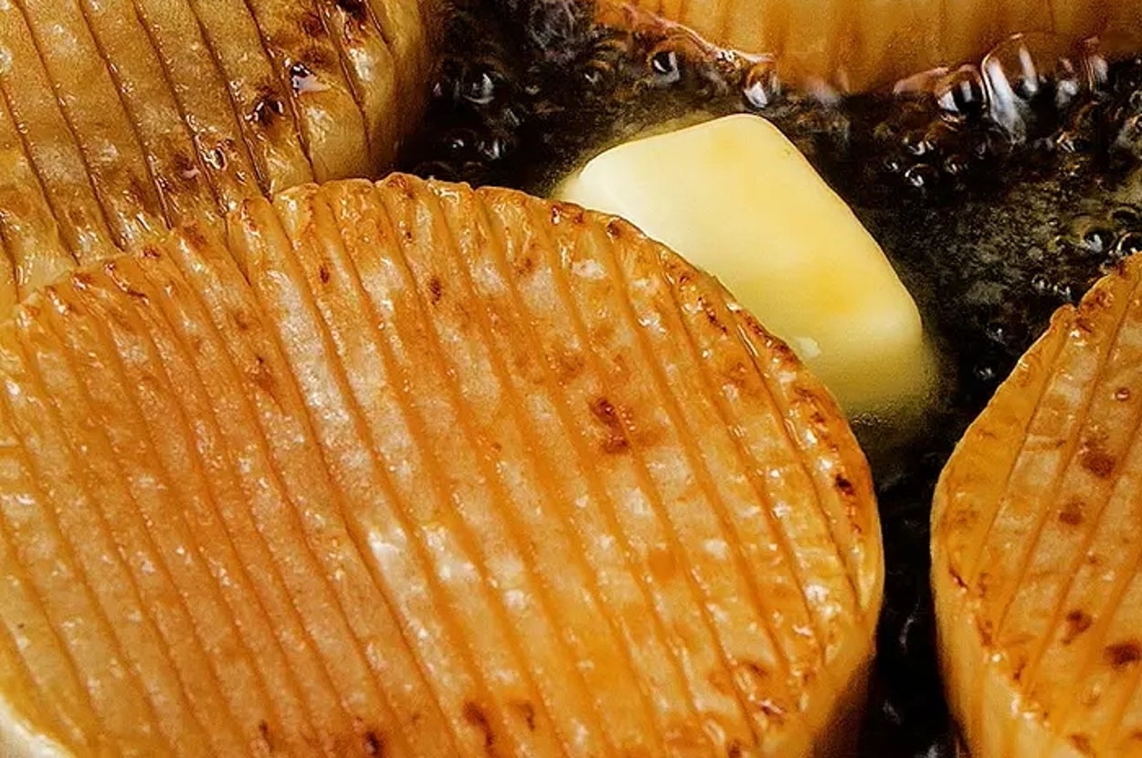 大根のステーキがバターと一緒に焼かれている様子。