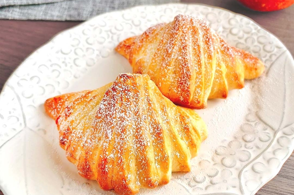 皿に盛られた二つの焼き立てアップルパイが置かれている。右奥にリンゴが見える。