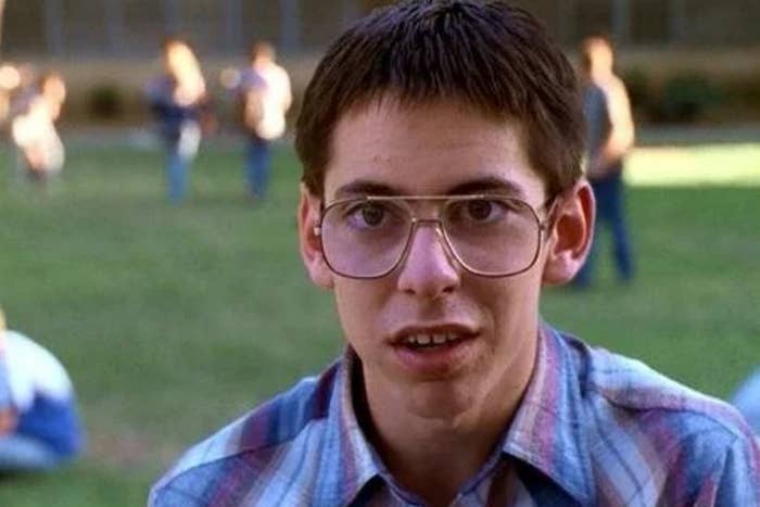 Young idiosyncratic   with abbreviated  hair, wearing ample  glasses and a plaid shirt, lasting  outdoors. Others are disposable   successful  the blurry background