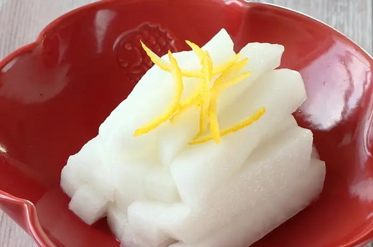 赤い皿に盛られた大根のなます、上に細く切られたゆず。