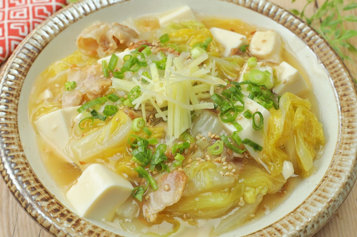 皿に盛られた豆腐と白菜の煮物。上に細切りの生姜と刻みネギがトッピングされている。