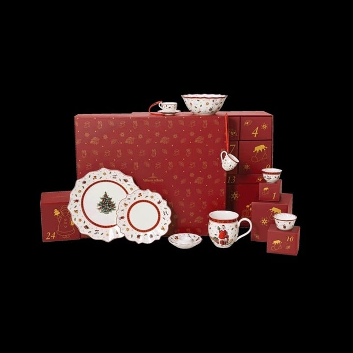 Holiday-themed porcelain tea set with decorative dishes and cups displayed next to a red box, marked with numbered holiday countdown drawers
