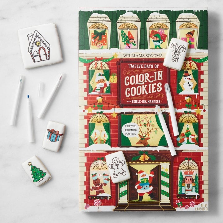 Cookie decorating set with a holiday theme, featuring edible markers and illustrated cookies, including a reindeer and gingerbread house