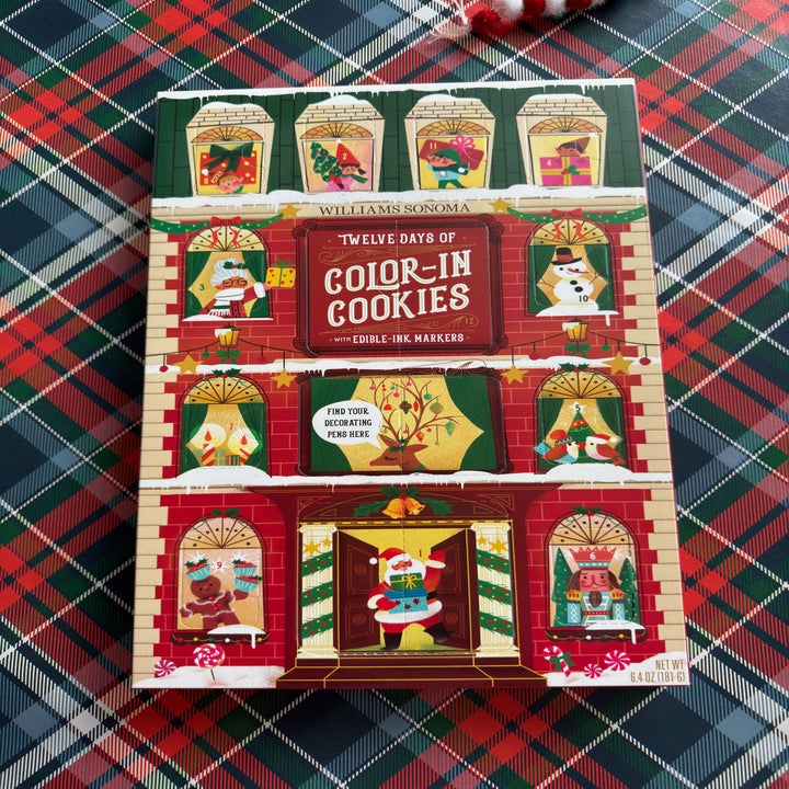 Box of "Twelve Days of Color-In Cookies" by Williams Sonoma on plaid surface, with holiday-themed illustrations on the cover
