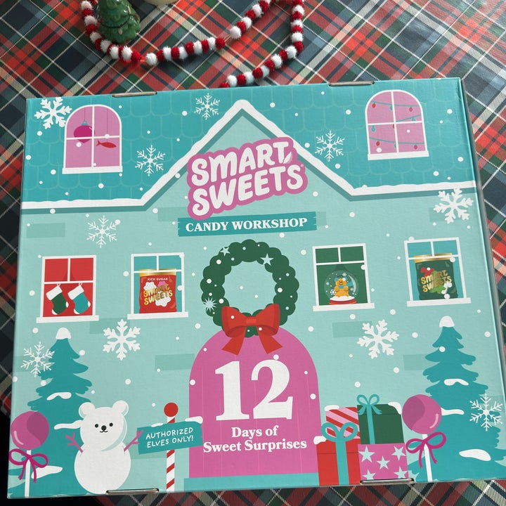 Candy advent calendar with festive design, including a wreath, gifts, snowflakes, and a polar bear. Text: "Smart Sweets Candy Workshop, 12 Days of Sweet Surprises."