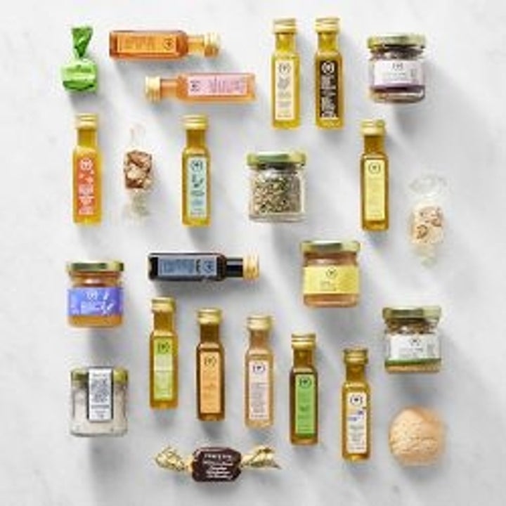 Assorted small bottles and jars of oils, herbs, and seasonings arranged on a surface, showcasing a variety of gourmet ingredients