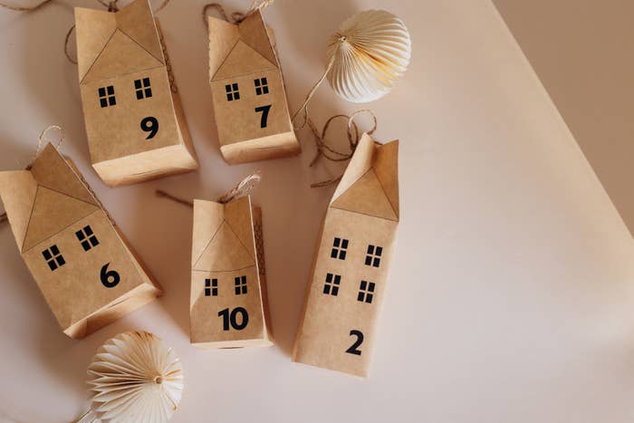 Five small, house-shaped paper bags with numbers 2, 6, 7, 9, and 10. Two ornamental spheres nearby