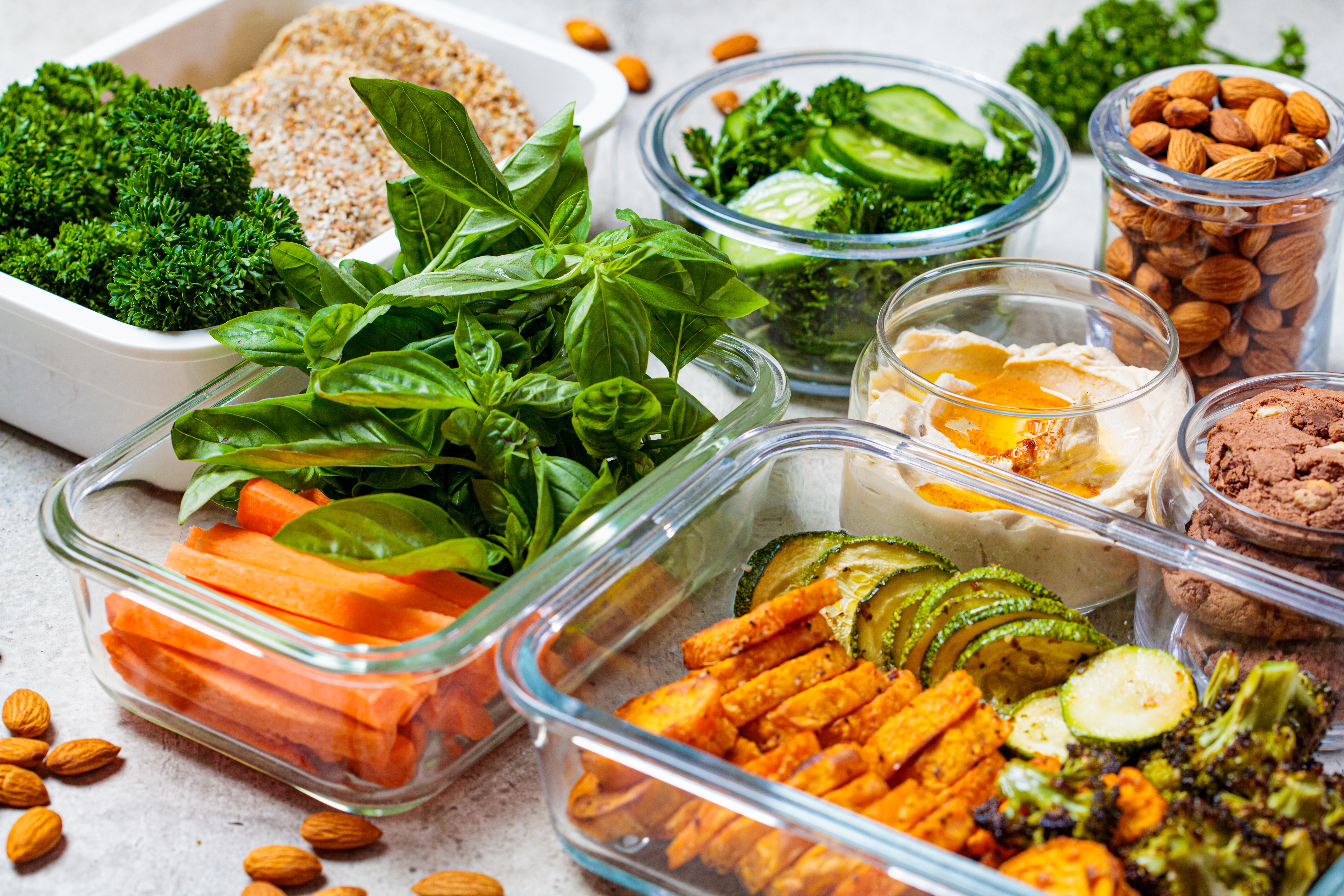 Healthy repast prep with veggies, nuts, and herbs shown successful solid containers, featuring carrots, broccoli, zucchini, and almonds connected a room counter