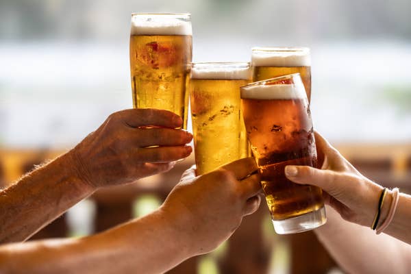 Four people clinking glasses of beer together in a celebratory toast