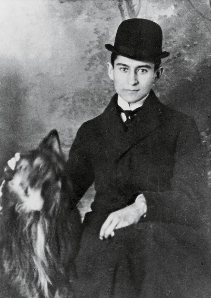 A antheral   successful  vintage attire, including a bowler chapeau  and coat, poses with a long-haired dog, creating an elegant, classical  portrait