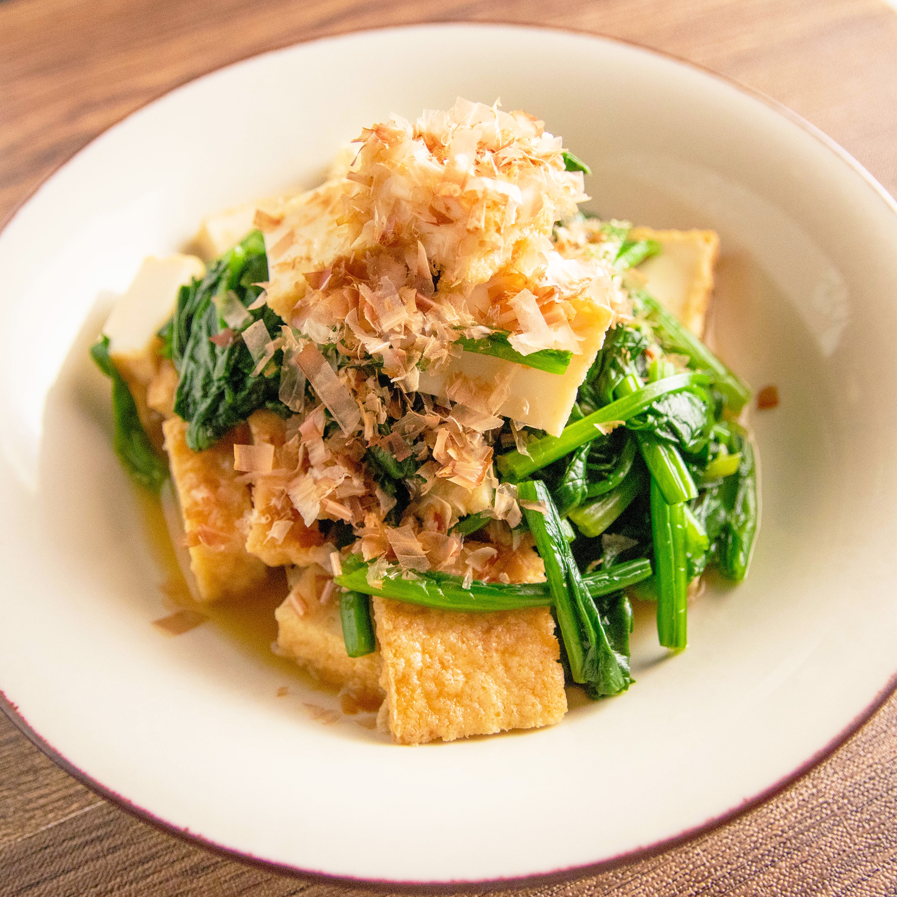 お皿に盛られた厚揚げとほうれん草の和風サラダ。上に削り節がのっている。