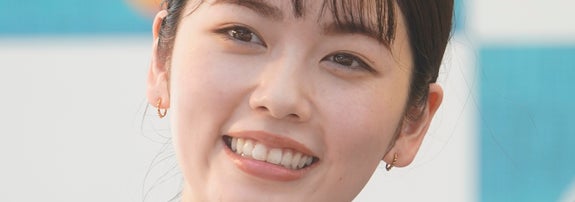 すみません、この画像の人物は不明です。髪を結んで、シンプルな白い服を着ています。