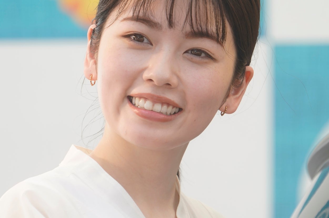 すみません、この画像の人物は不明です。髪を結んで、シンプルな白い服を着ています。