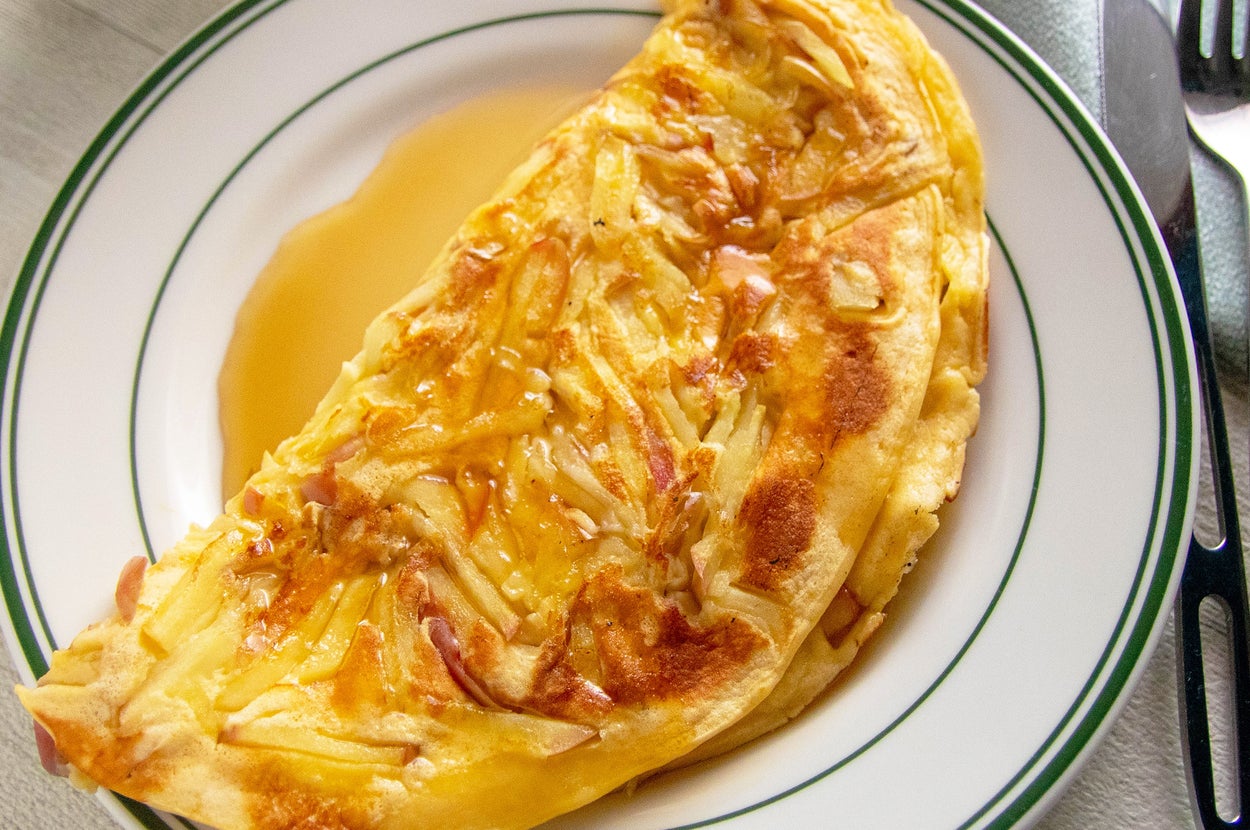 皿に盛られたチーズたっぷりのオムレツ。横にフォークとナイフが置かれている。