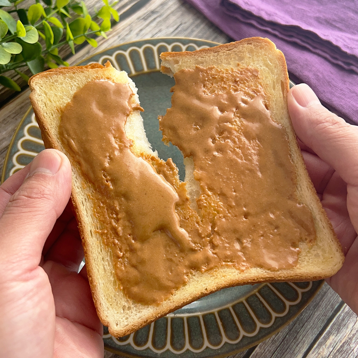 人がピーナッツバターを塗ったトーストを手で割ろうとしている様子。