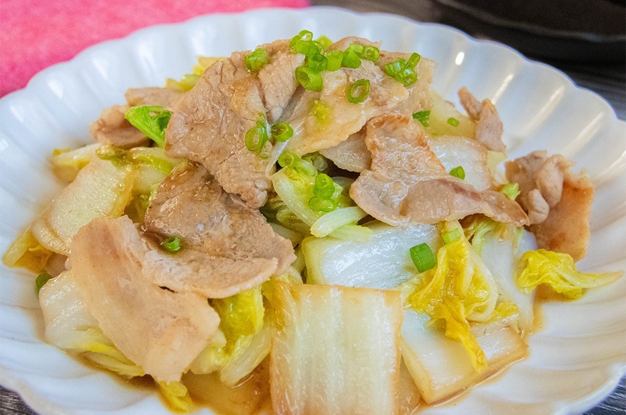 白菜と豚肉のゆずコショウ炒めが白い皿に盛られている。テーブルに箸が置かれている。