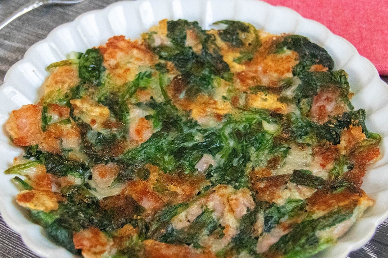 皿に盛られたほうれん草とベーコンとチーズのガレット。カトラリーが横に置かれている。