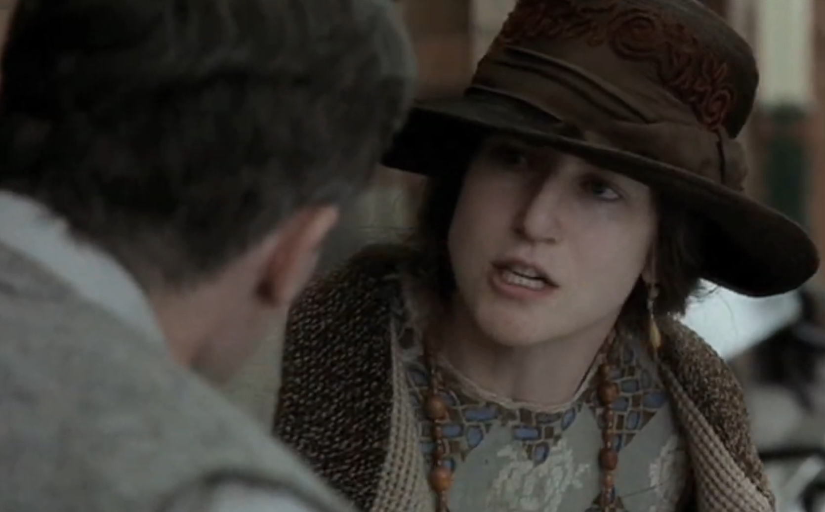 Two radical   successful  play  costumes engaging successful  conversation; 1  wears a chapeau  and coat