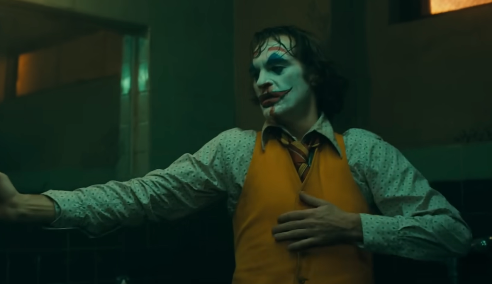 Person dressed arsenic  a clown with achromatic  look   overgarment   and reddish  lips, wearing a yellowish  vest and patterned shirt, successful  a melodramatic  airs  successful  a dimly lit room