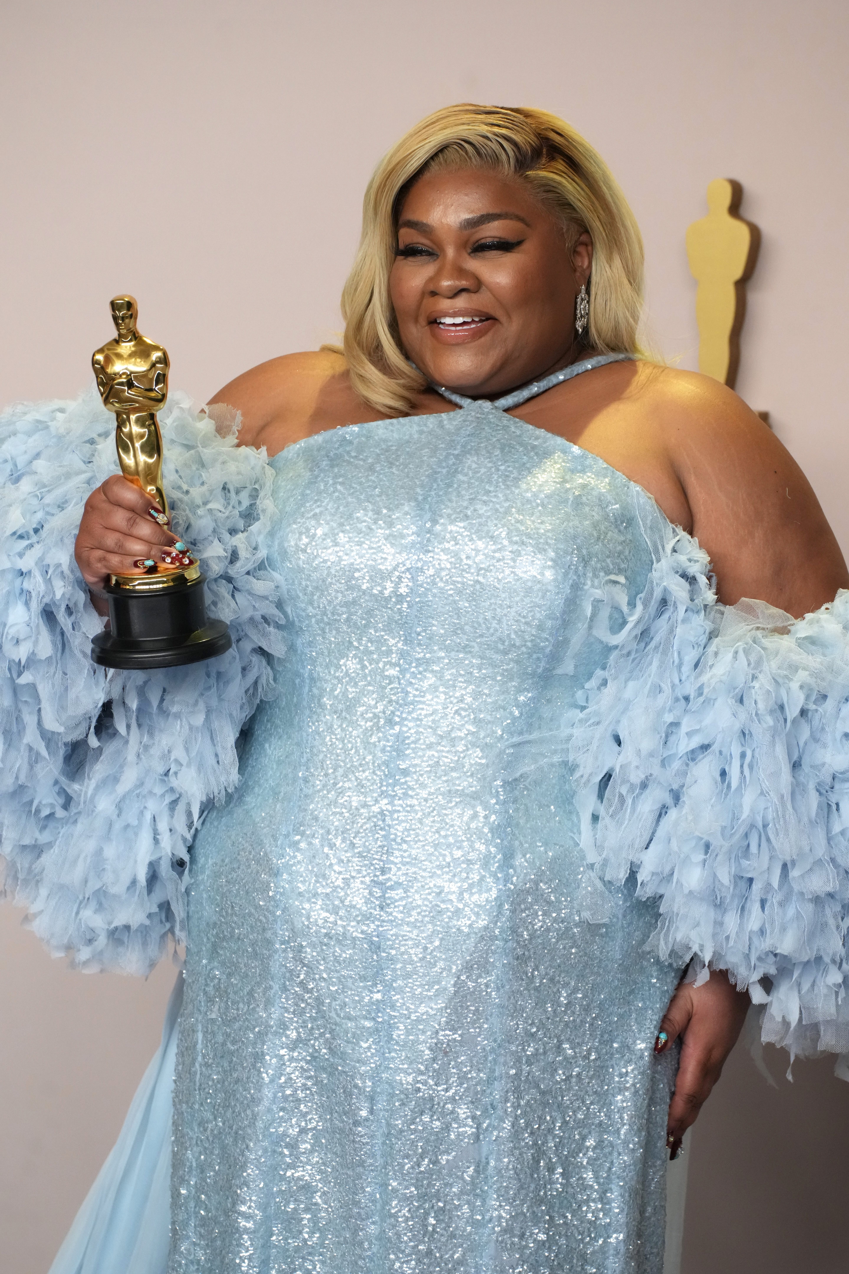 Person smiling successful  a shimmering gown with feathered sleeves, holding an grant  statue