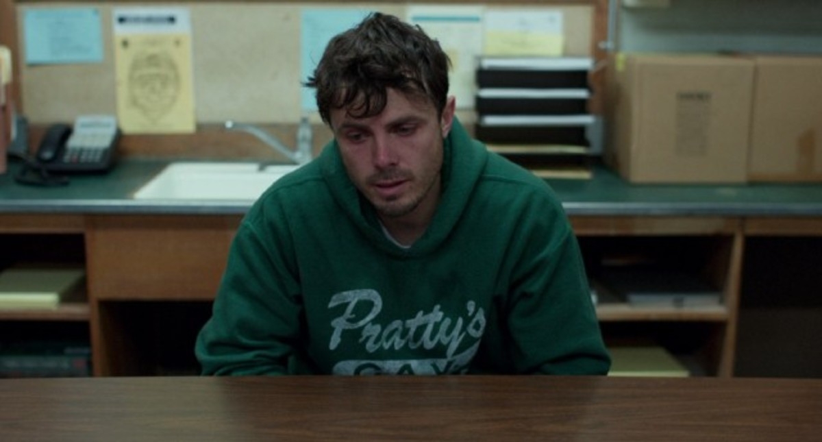 A idiosyncratic   successful  a greenish  hoodie sits astatine  a array  with files and a telephone  disposable   successful  the background