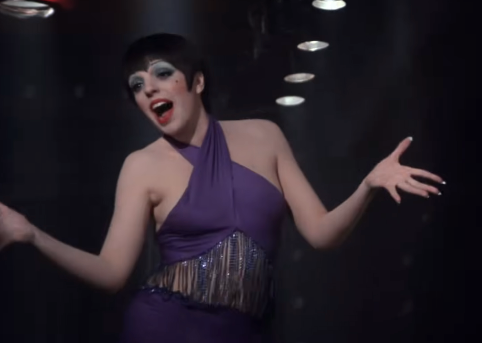 Performer successful  a sleeveless, fringed formal  sings expressively connected  signifier    with arms unfastened  wide