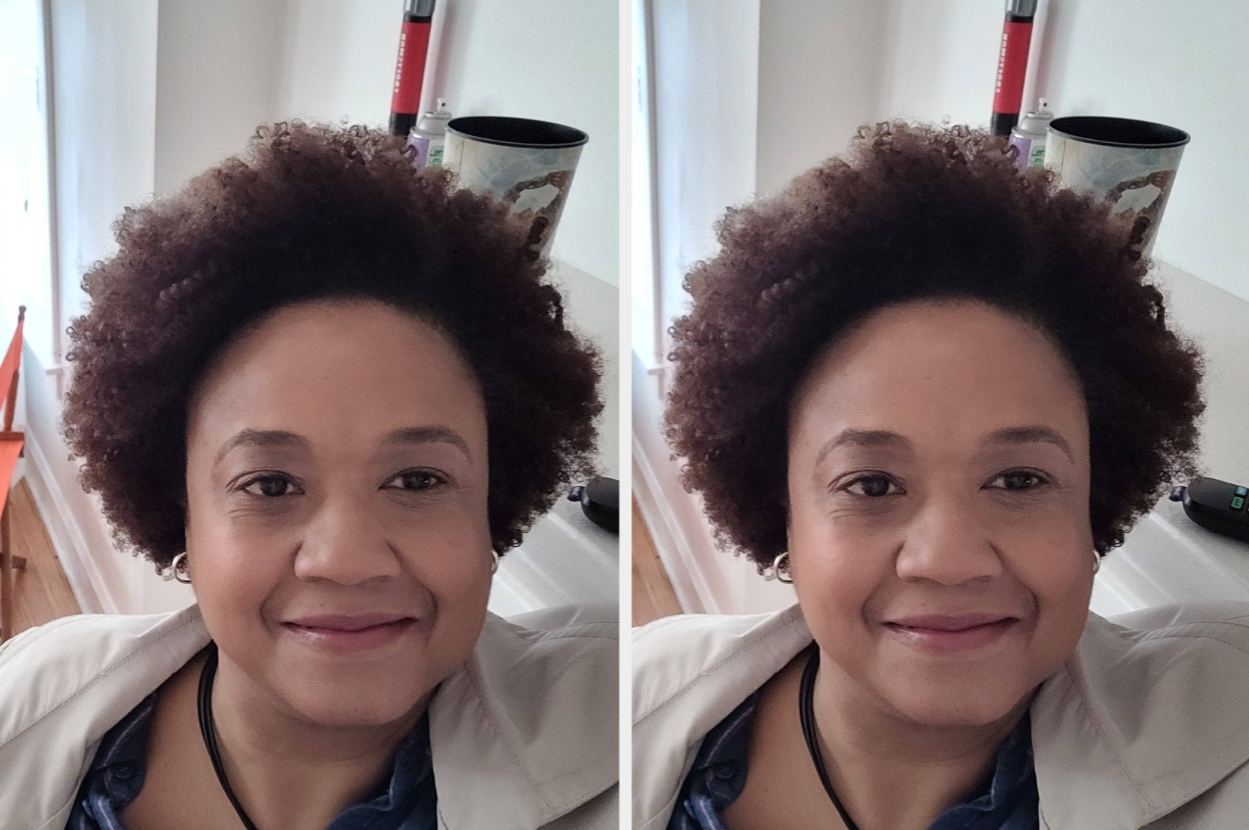 Person smiling at the camera in a home setting, wearing a light jacket and necklace, in front of a blurred background with furniture