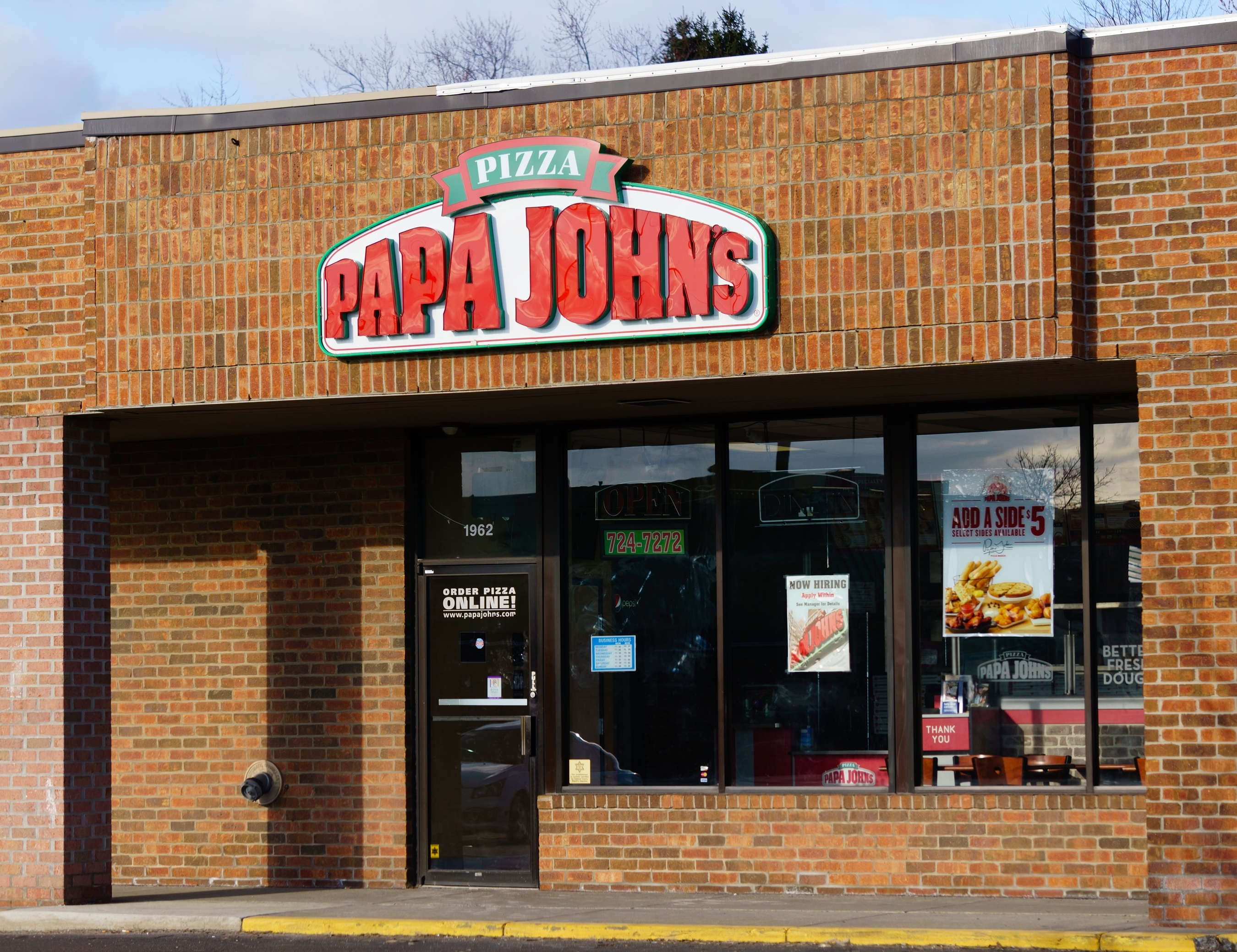 Papa John's storefront showing promotional posters on the windows and a neon "Open" sign