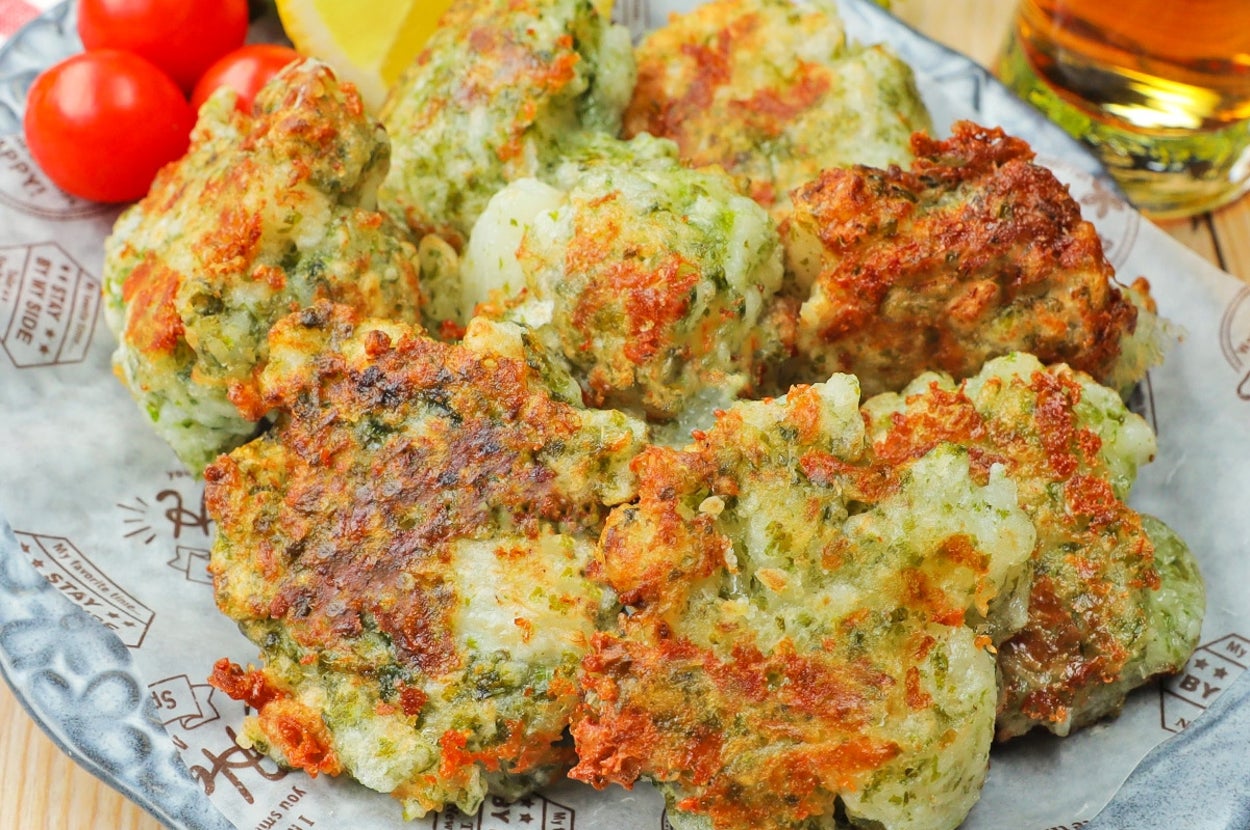 皿に盛られた緑の混ざったかき揚げとトマト、レモンのくし形切り。