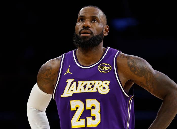 Basketball player in purple Lakers jersey stands with hands on hips during a game
