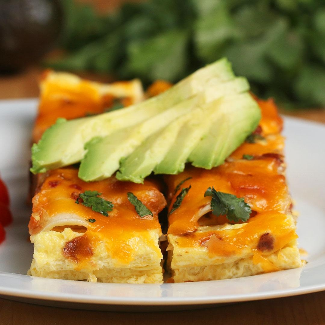 Egg bake topped with sliced avocado and herbs on a white plate