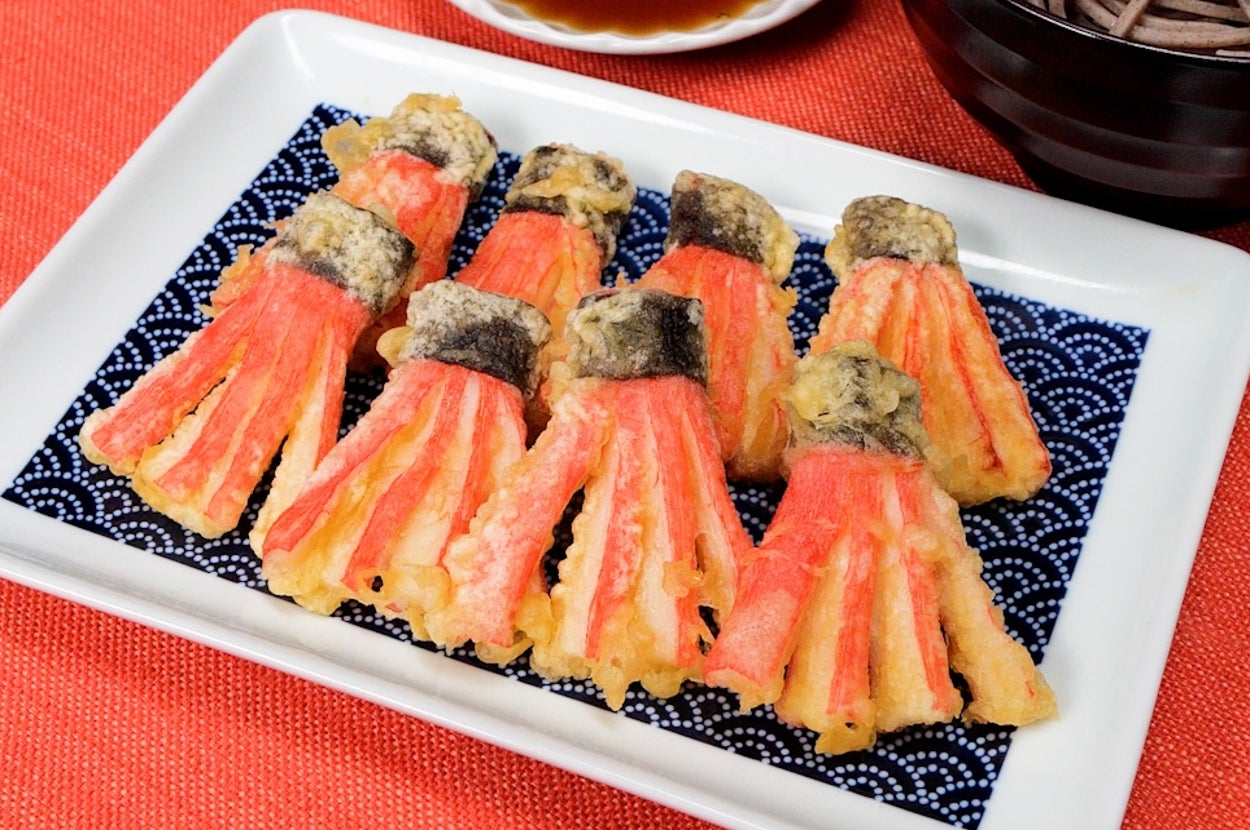 天ぷらの盛り合わせが白い皿に美しく並べられ、そば、つけ汁と共に食卓に置かれている様子。