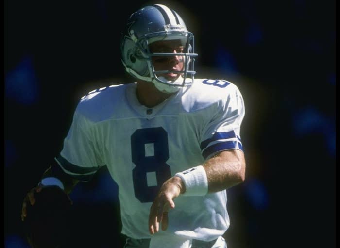 Football player in action, wearing a helmet and uniform with number 8, preparing to throw a pass during a game