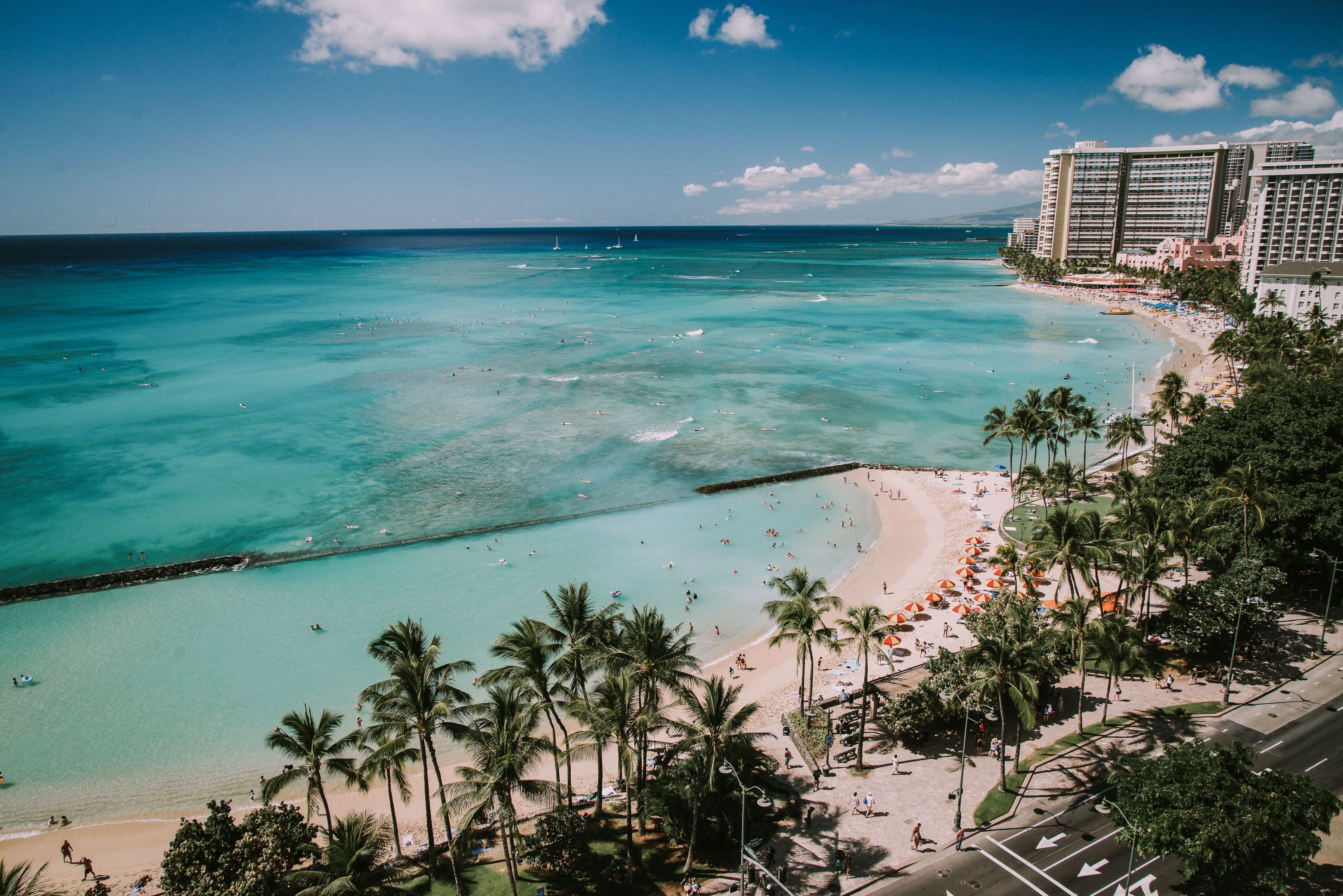Waikiki Beach with surfers and sunbathers, surrounded by high-rise hotels and thenar trees, nether a agleam bluish sky