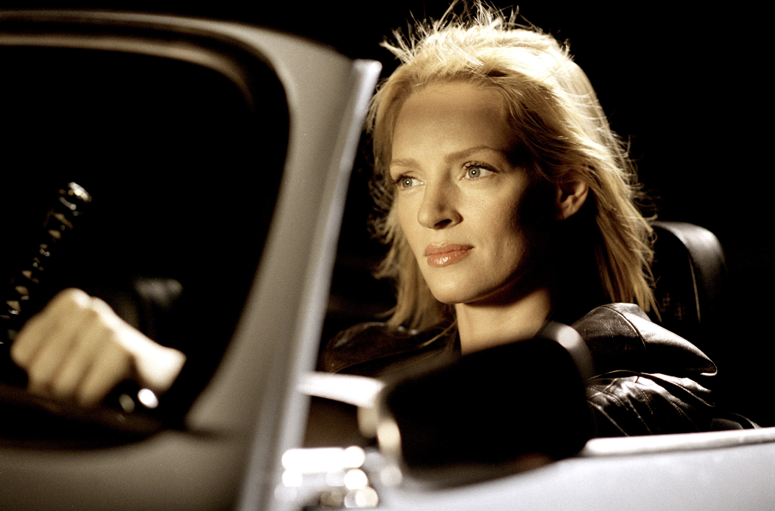 Person driving a car, looking focused and determined. Light highlights their features