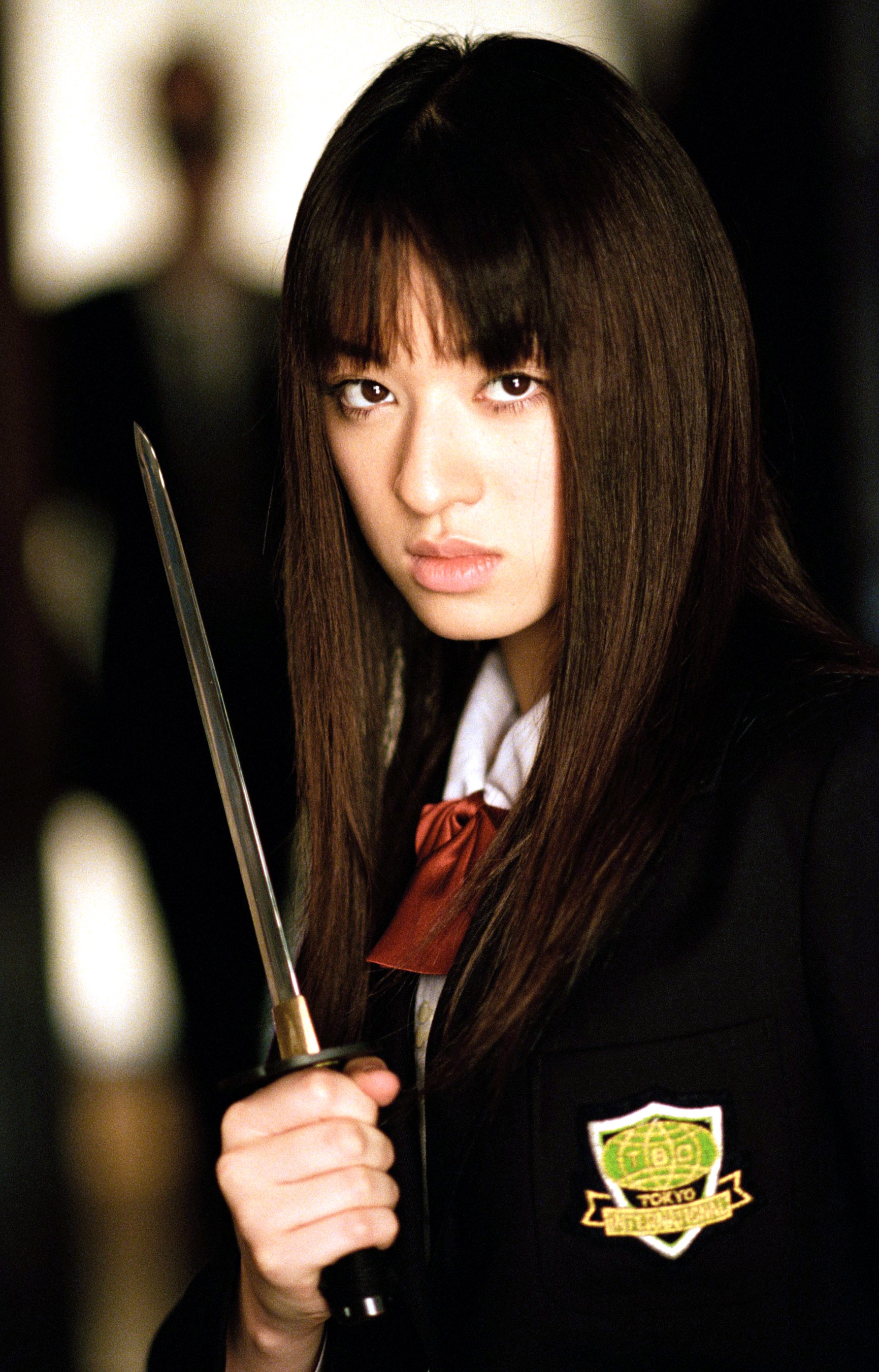 Person in a school uniform holds a sword, with a focused expression