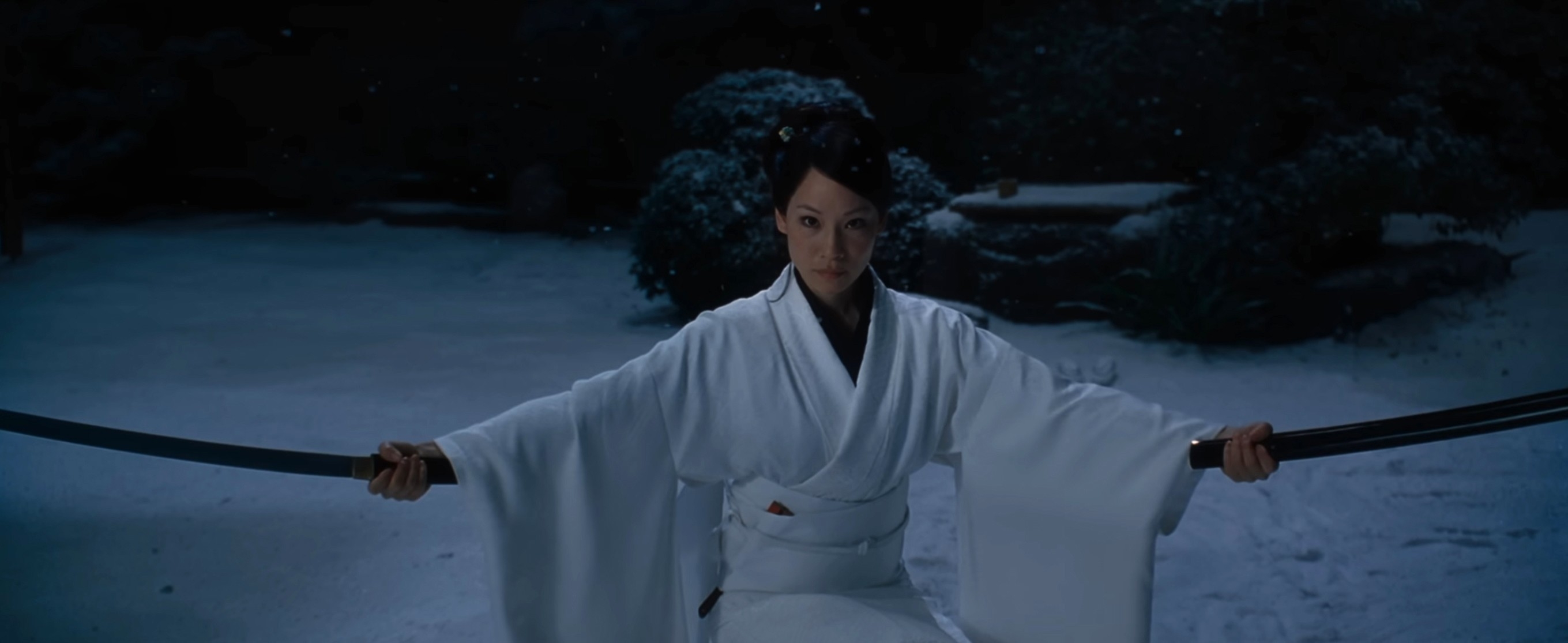A person in a white kimono wields two swords, standing in a snowy setting with focused expression