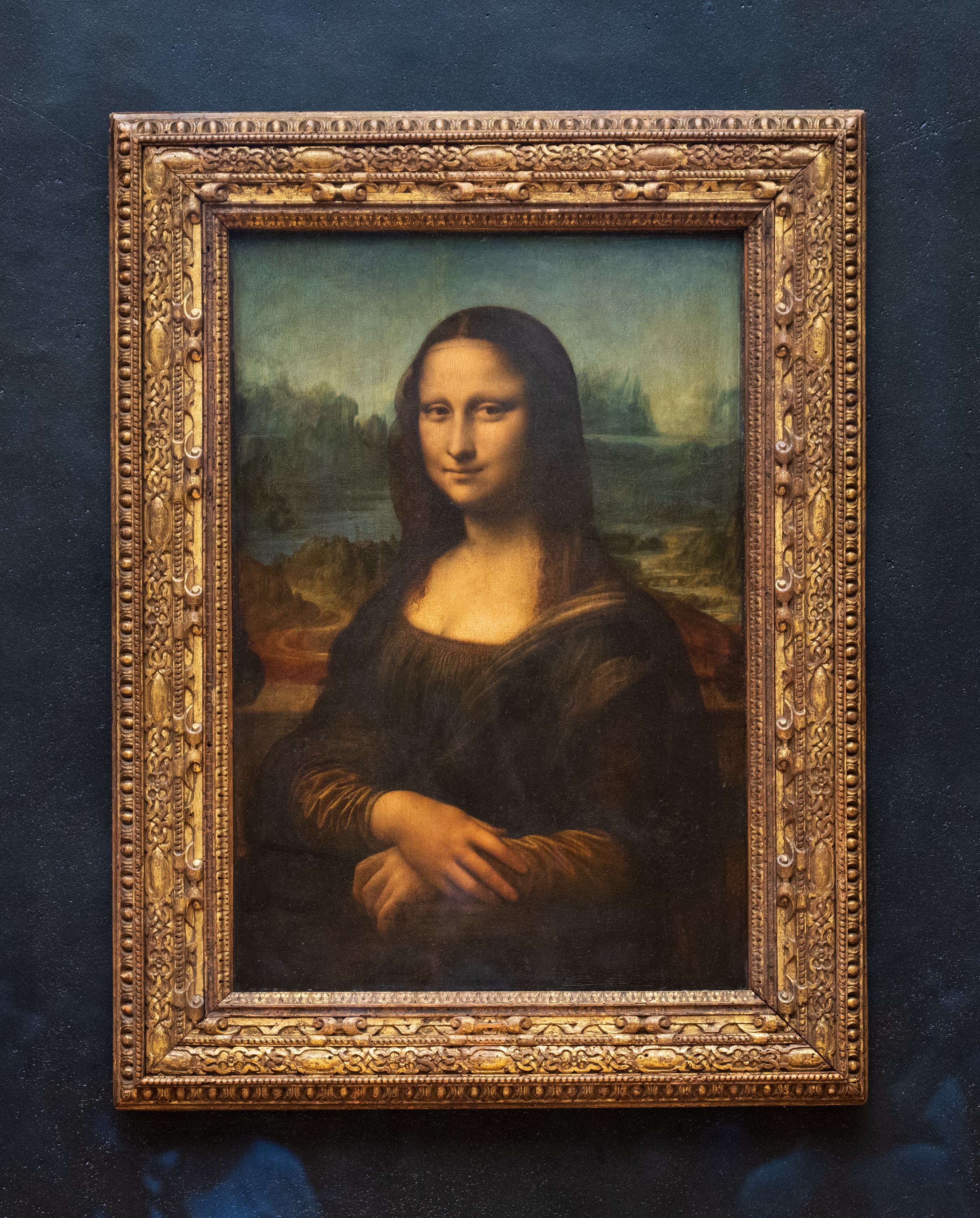 Portrait of Mona Lisa displayed successful an ornate framework astatine a museum, showcasing her serene look and clasped hands