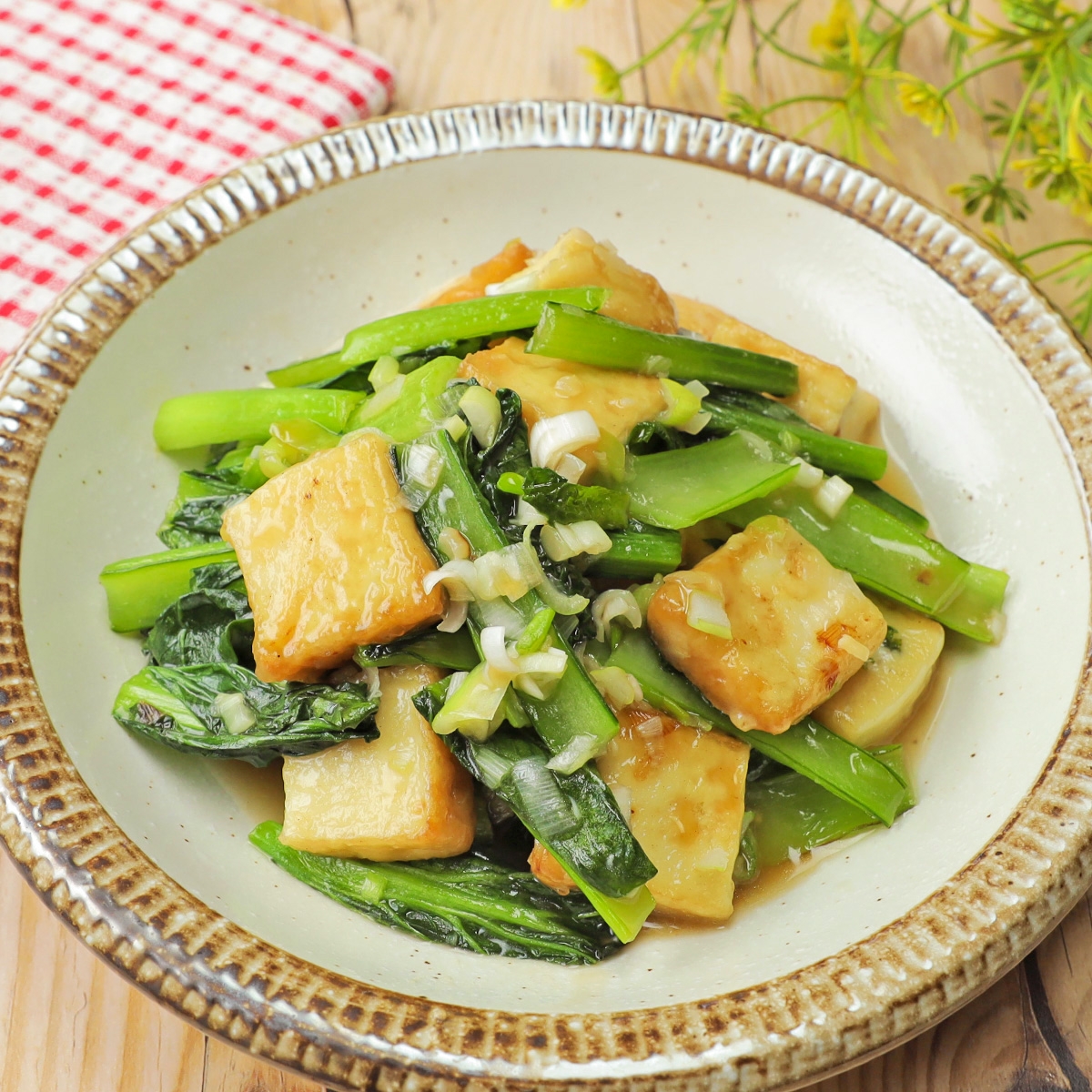 野菜と豆腐の炒め物が盛られた皿。緑の葉野菜と豆腐が食欲をそそる。